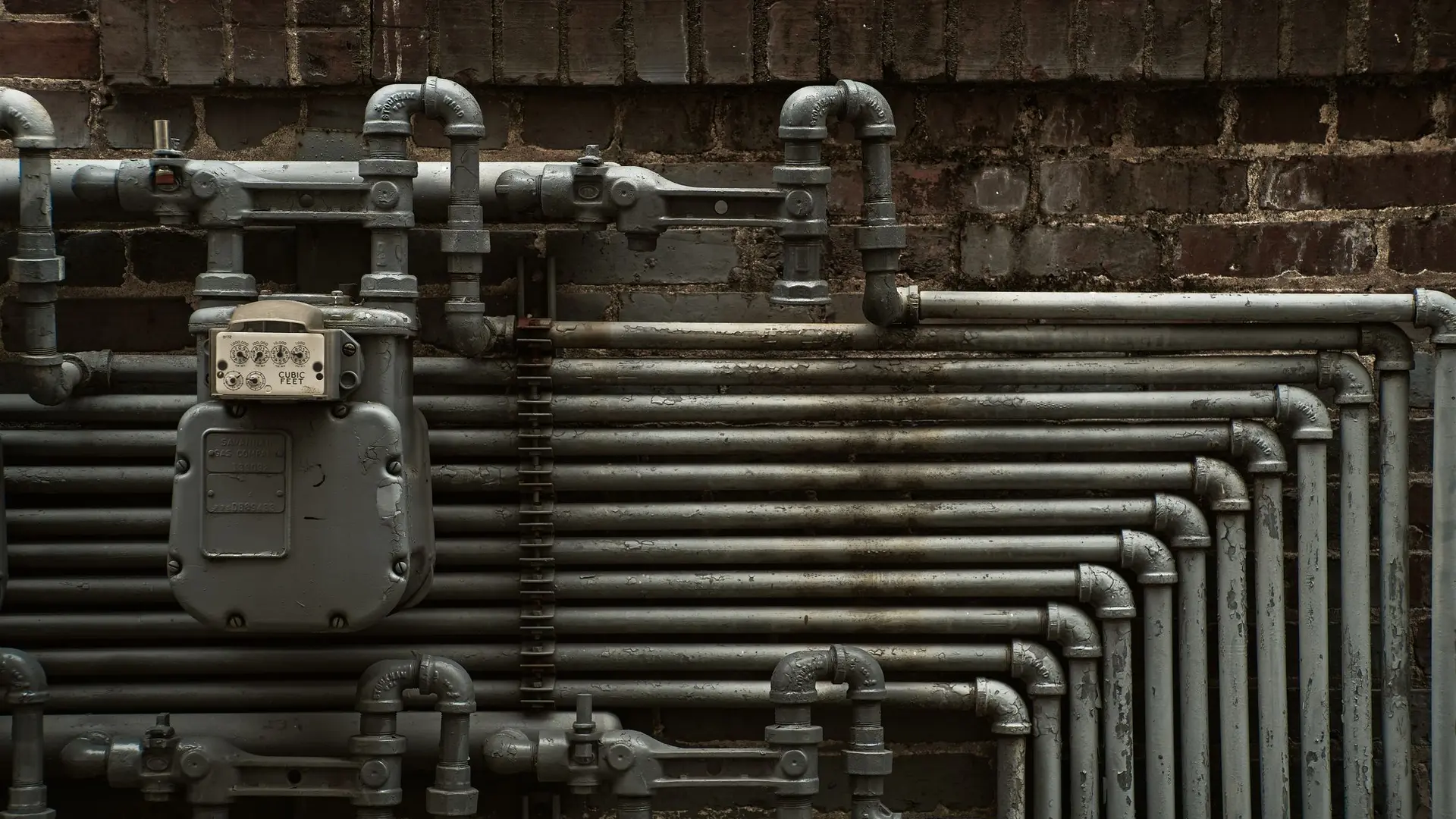 Gas pipework and a meter on a brick wall
