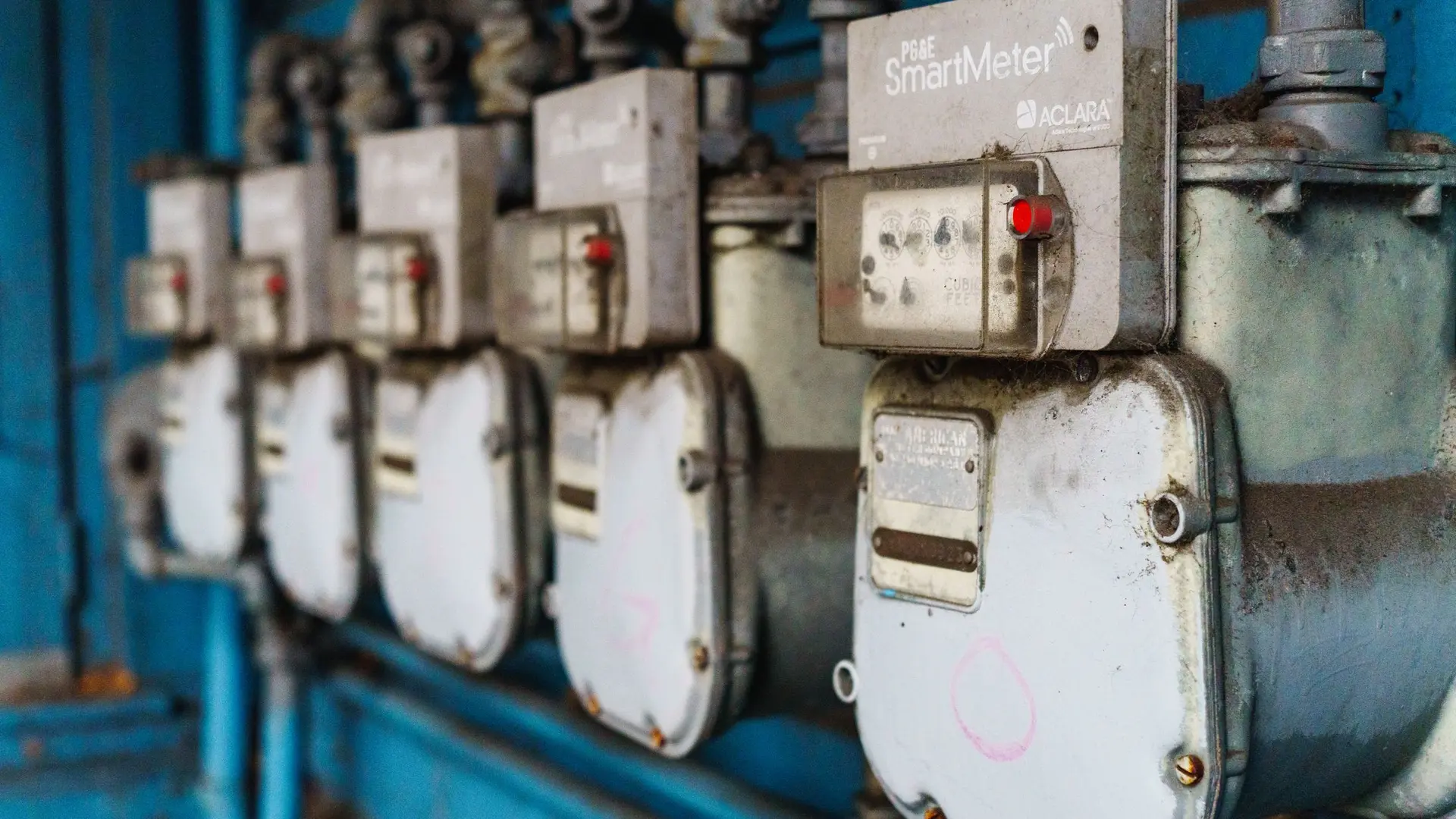 A row of old gas meters mounted on a blue painted wall