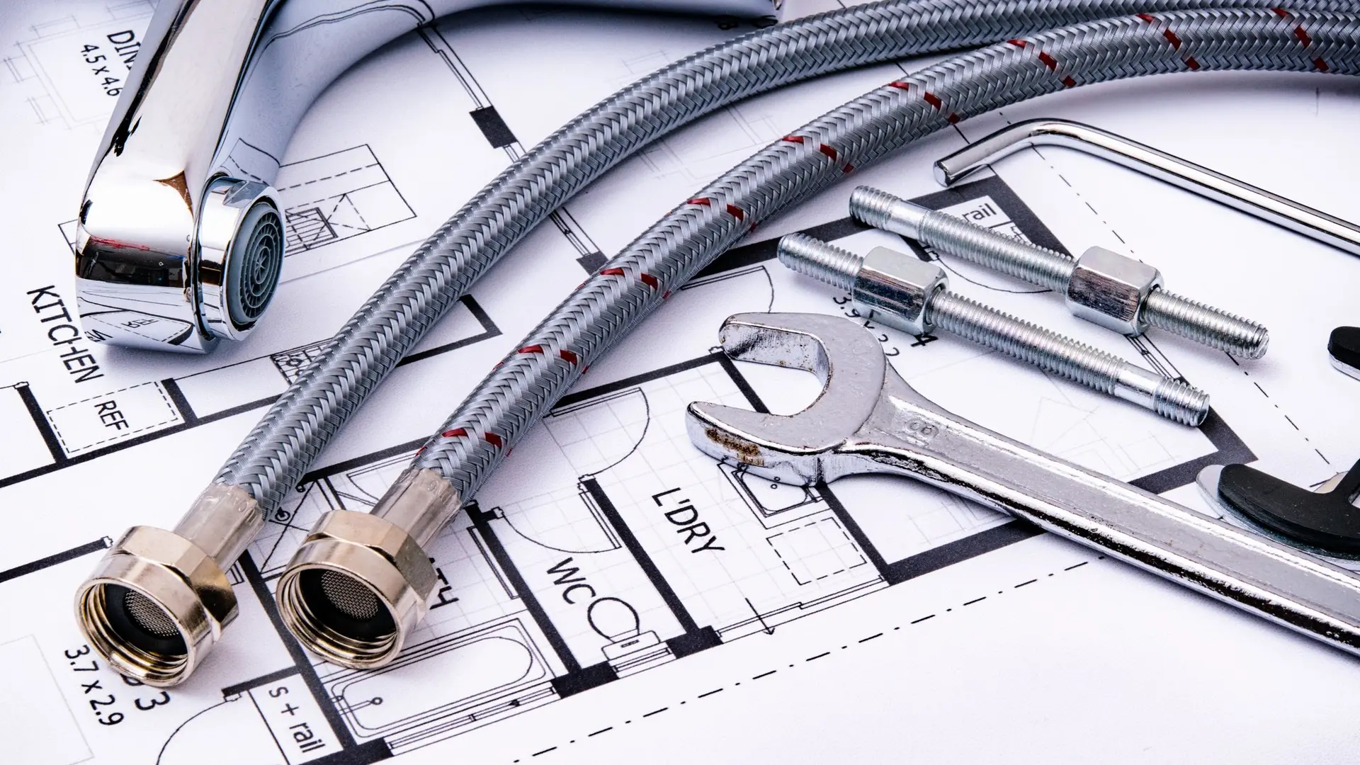 Flexible tap connectors and a spanner laid over a plumbing plan