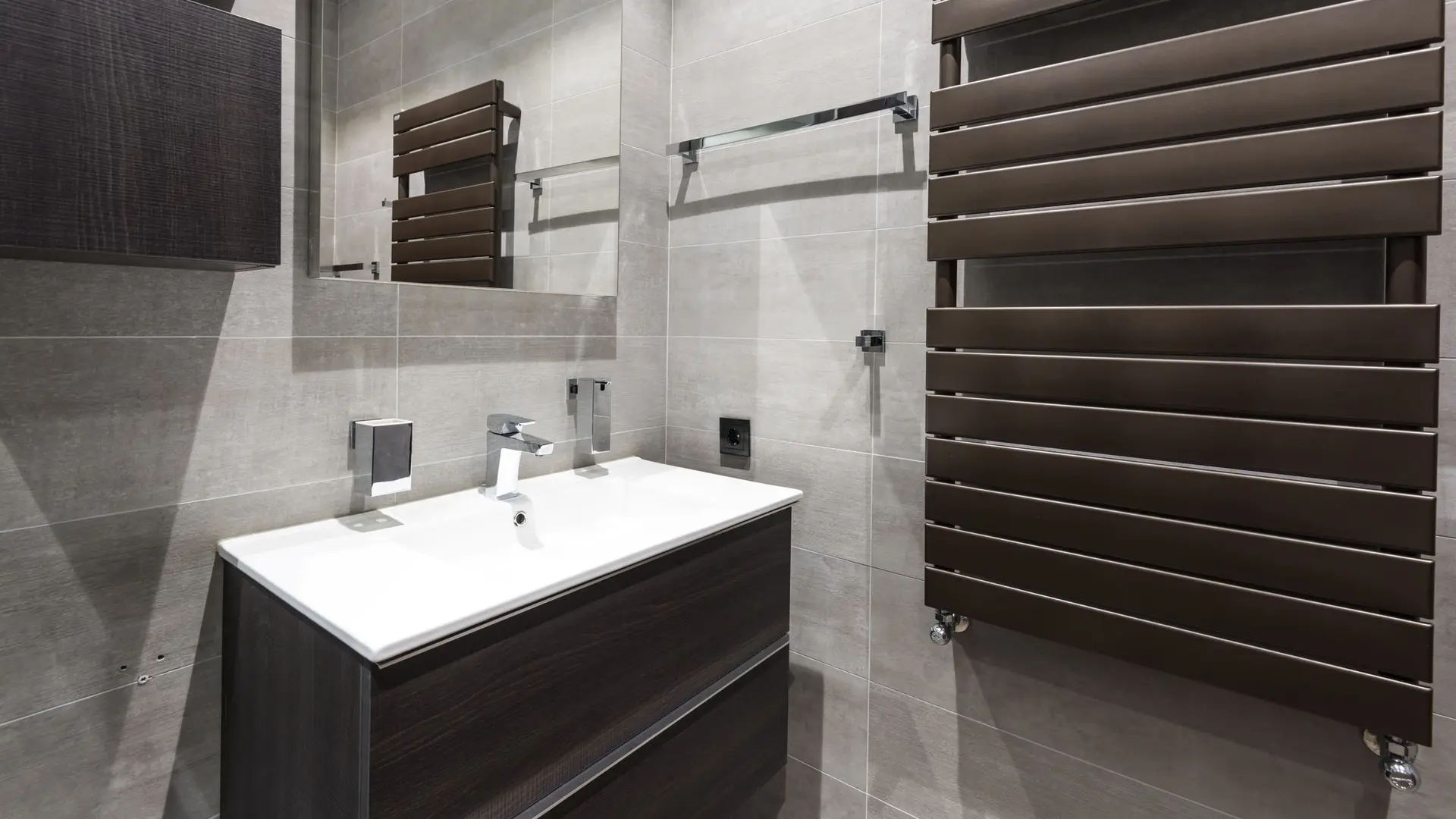 A modern bathroom with a dark towel radiator on the wall
