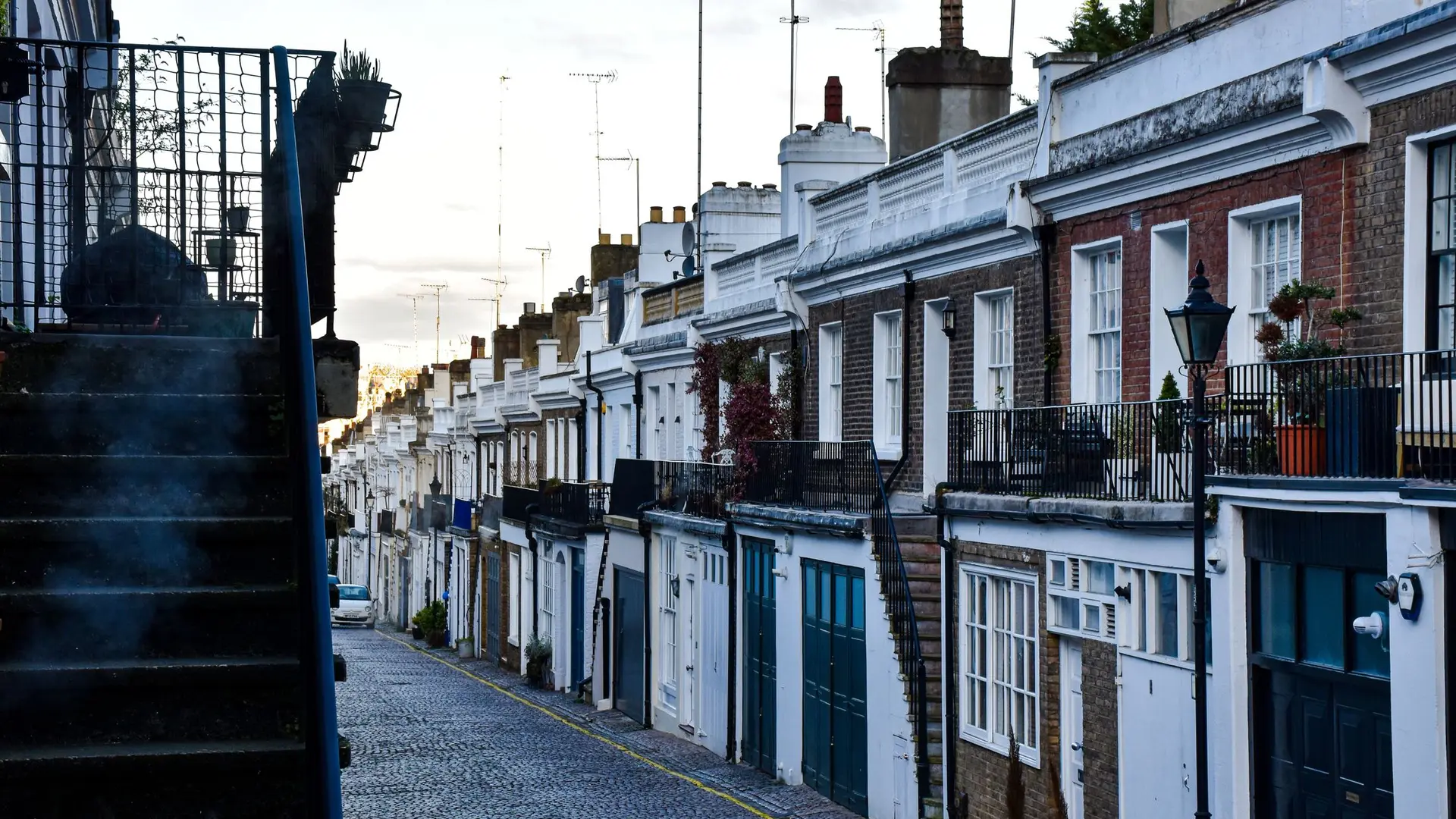 A cobbled London mews street lined with white painted houses
