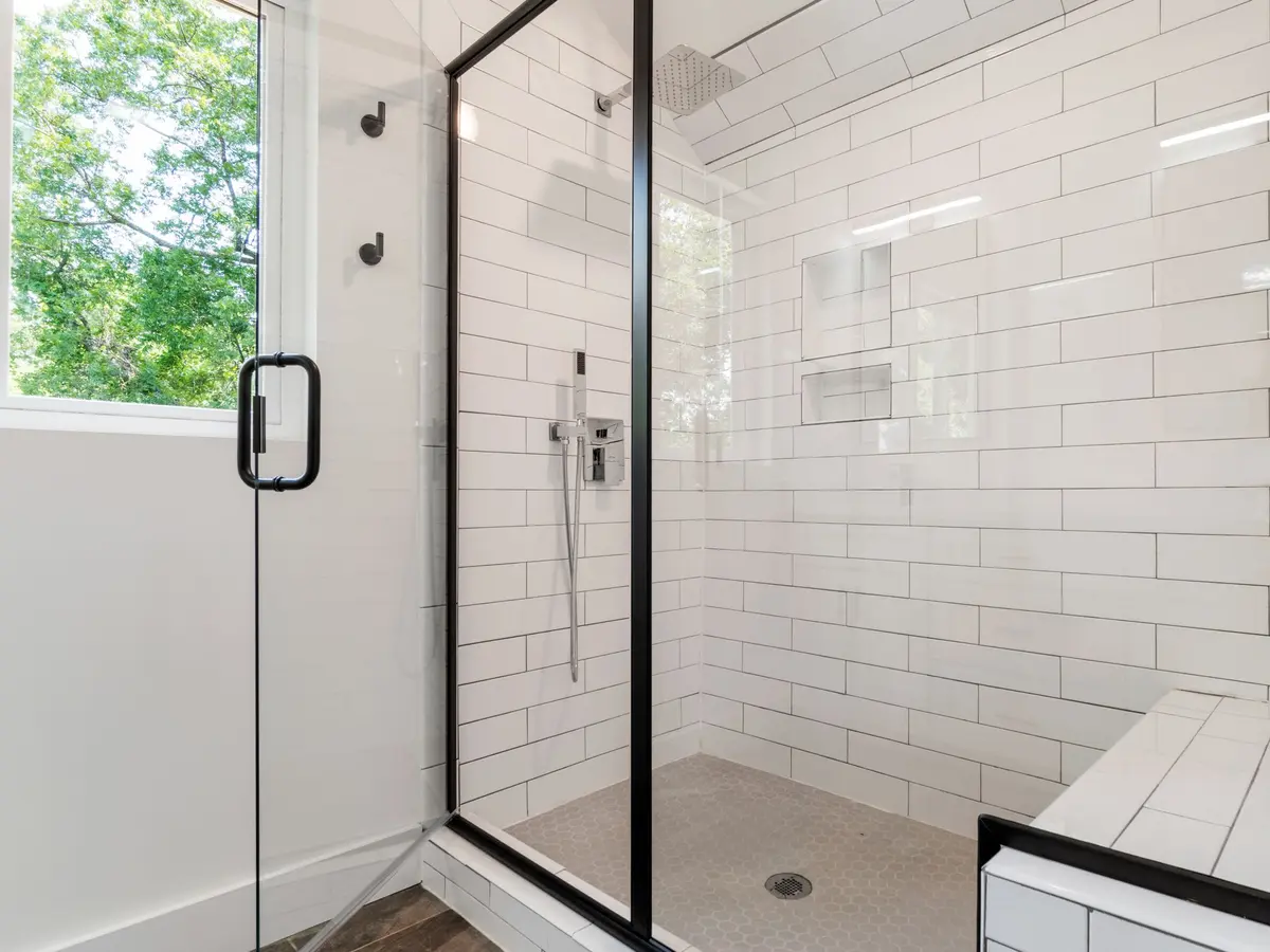 Walk-in shower with white metro tiles and a black frame