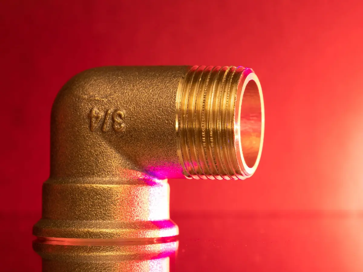 Brass elbow fitting on a red background