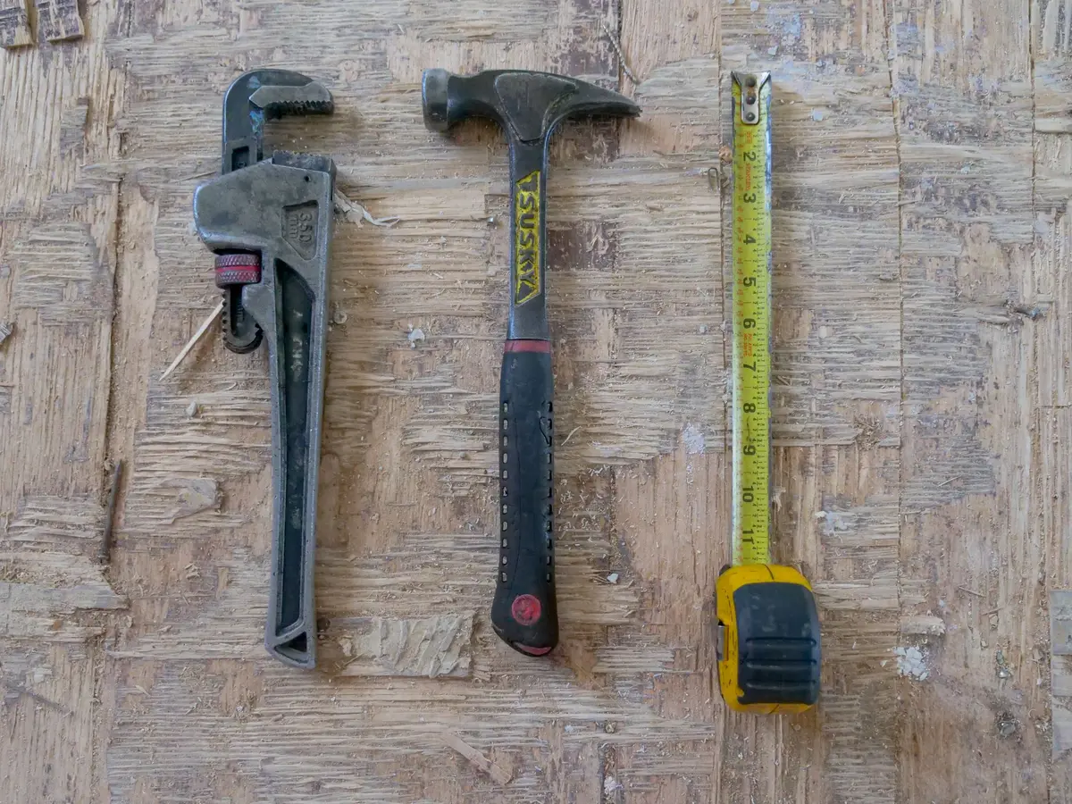 Pipe wrench, hammer and tape measure on a board