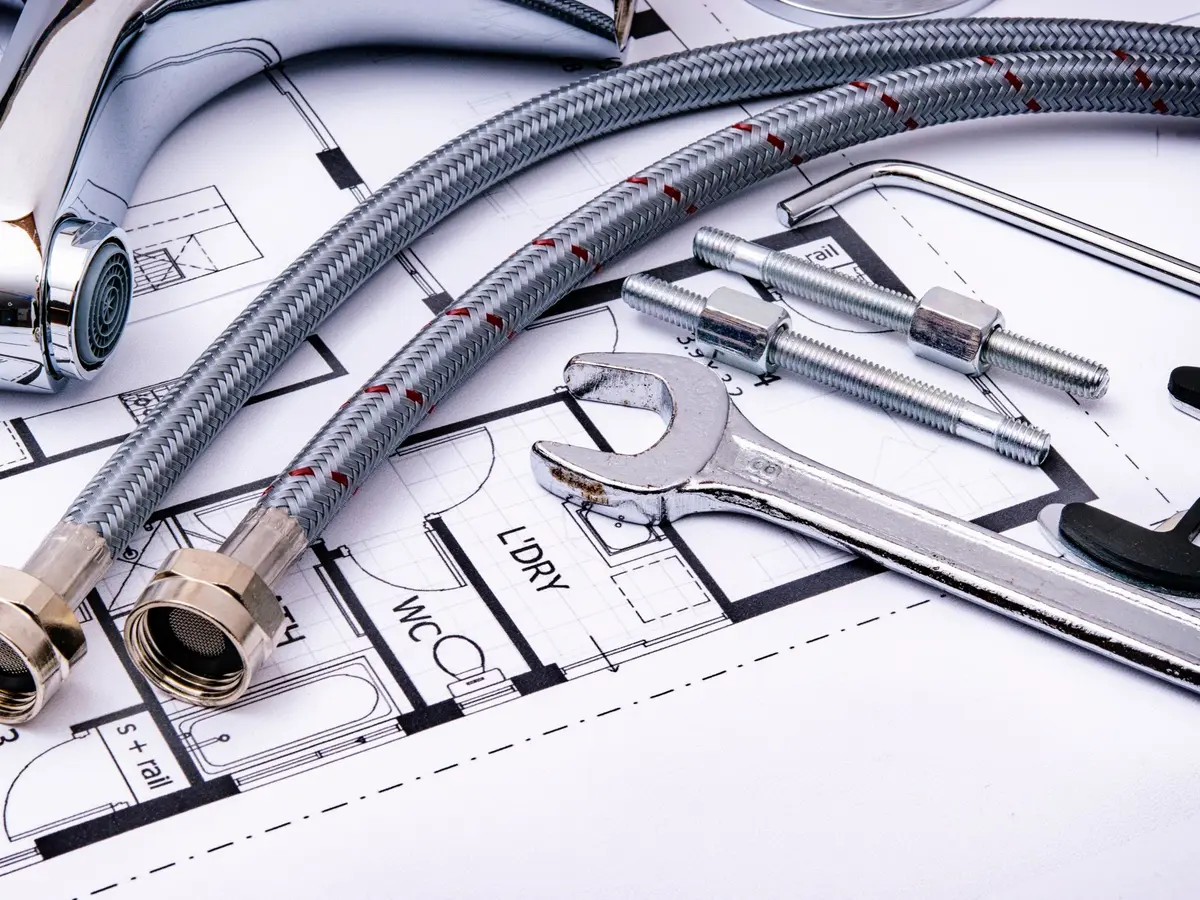 Flexible hoses and a spanner laid on a plumbing floor plan